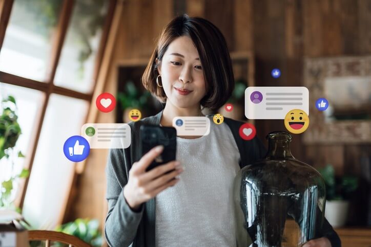 Young woman using smartphone in the living room at home, checking social media on mobile phone, receives notification, likes, views and comments.